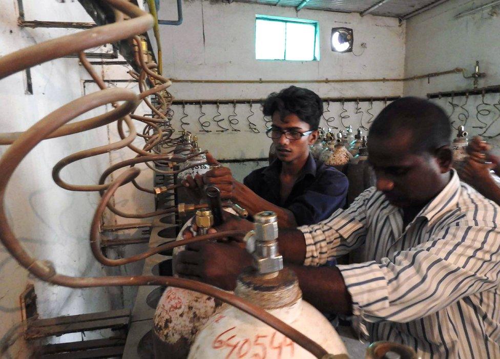 Workers examining oxygen cylinders at the hospital