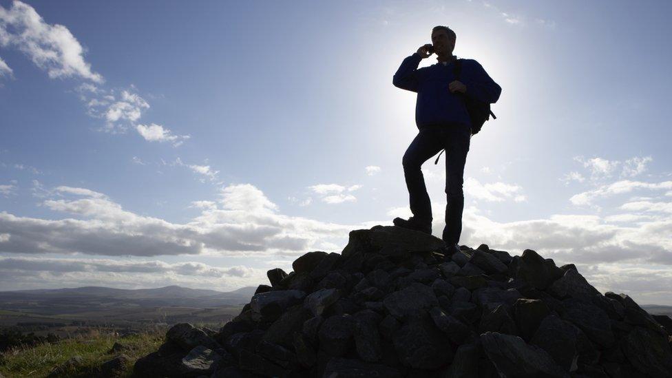 man on phone on top of mountain