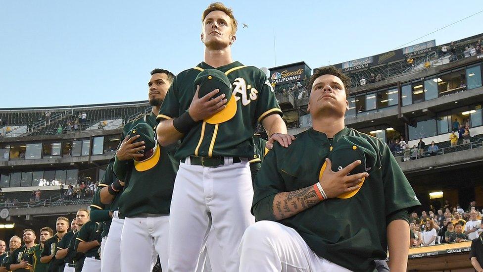 Baseball player Bruce Maxwell of the Oakland Athletics kneeling during the national anthem.