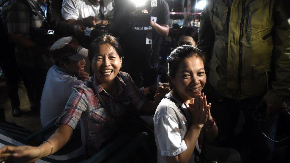 Family members celebrating and looking emotional, as tv cameras film their reaction.