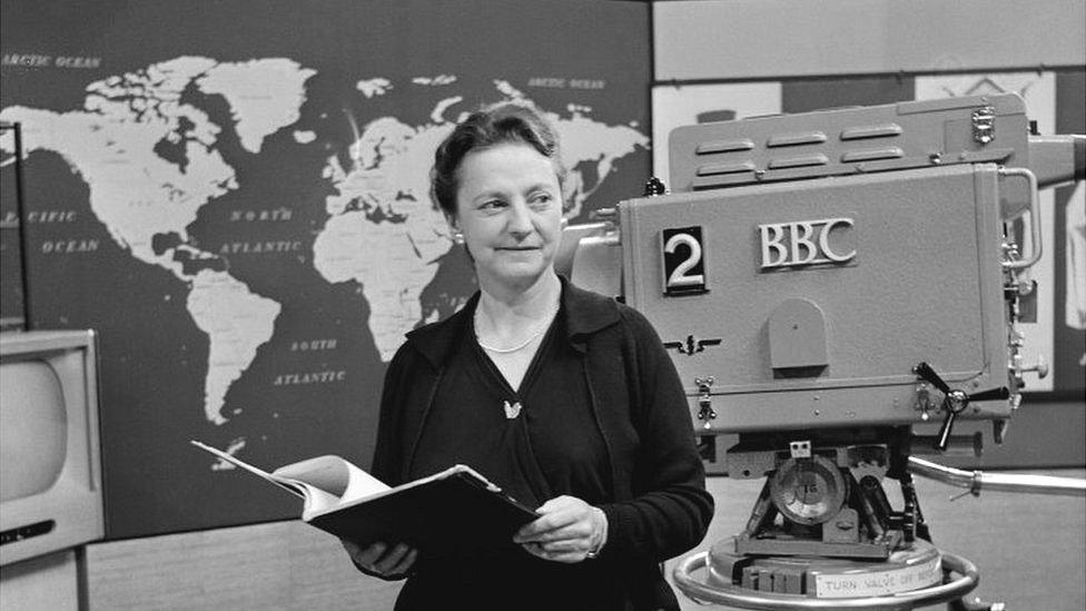 Ms Wyndham Goldie standing in front of a camera in a BBC television studio in 1958