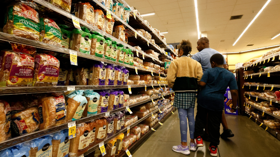 A man and two children in the bread aisle of a US supermarket