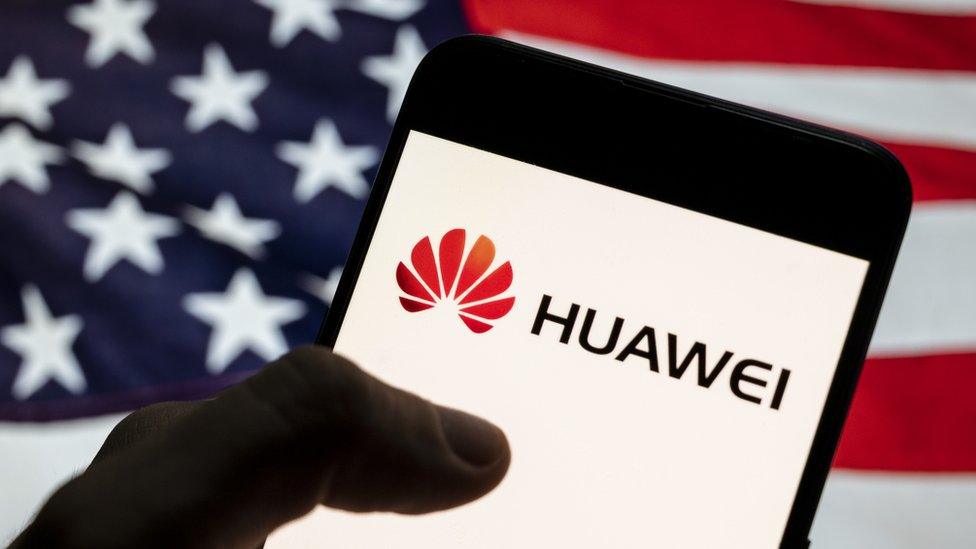 Huawei logo on smartphone in front of US flag.