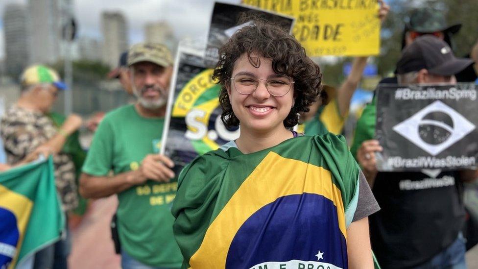 Sofia poses for a photo wrapped in a Brazilian flag