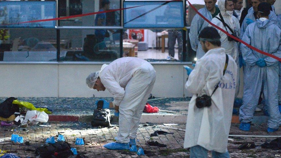 Turkish police officers search the area after a explosion in Suruc, Sanliurfa province, Turkey (20 July 2015)