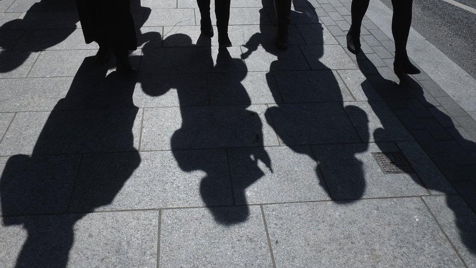 Shadows of people walking on a pavement