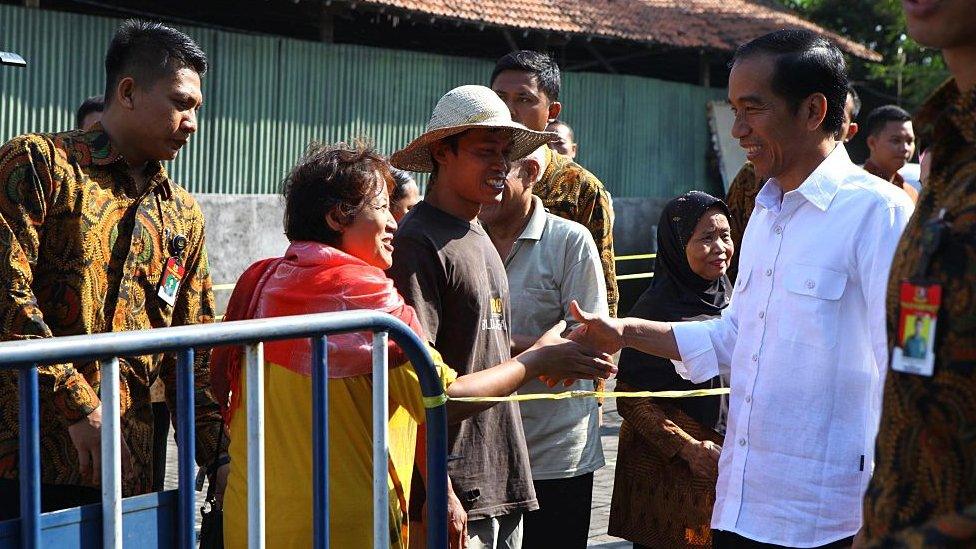 Indonesian President Joko Widodo gives money and food packages to poor people during Eid al Fitr celebration in Surakarta,