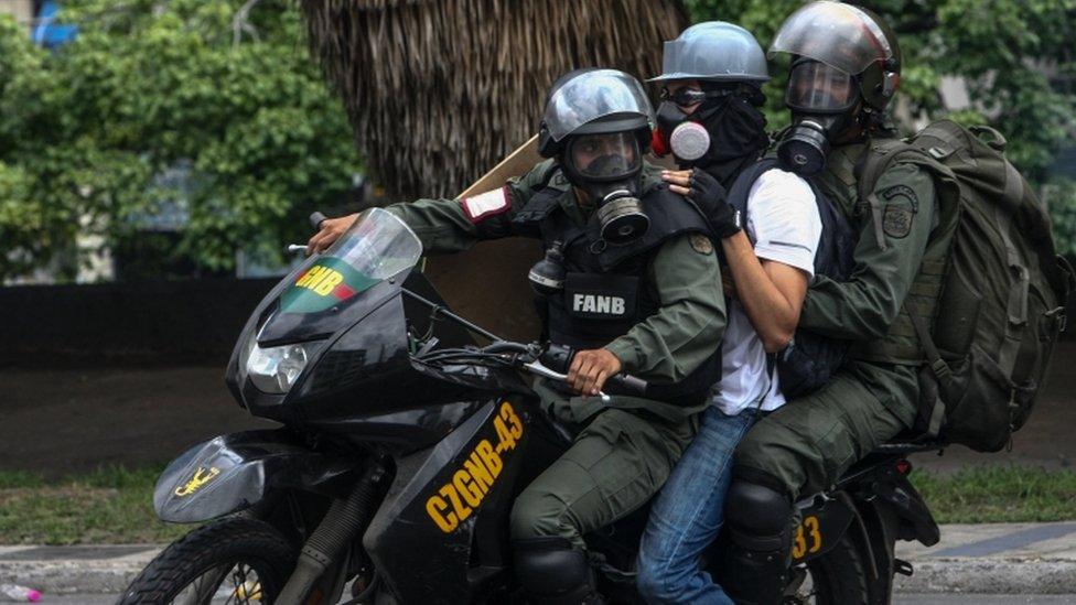 Members of Venezuelan Bolivarian Guard arrest an opposition sympathizer during a protest against the Government in Caracas, Venezuela