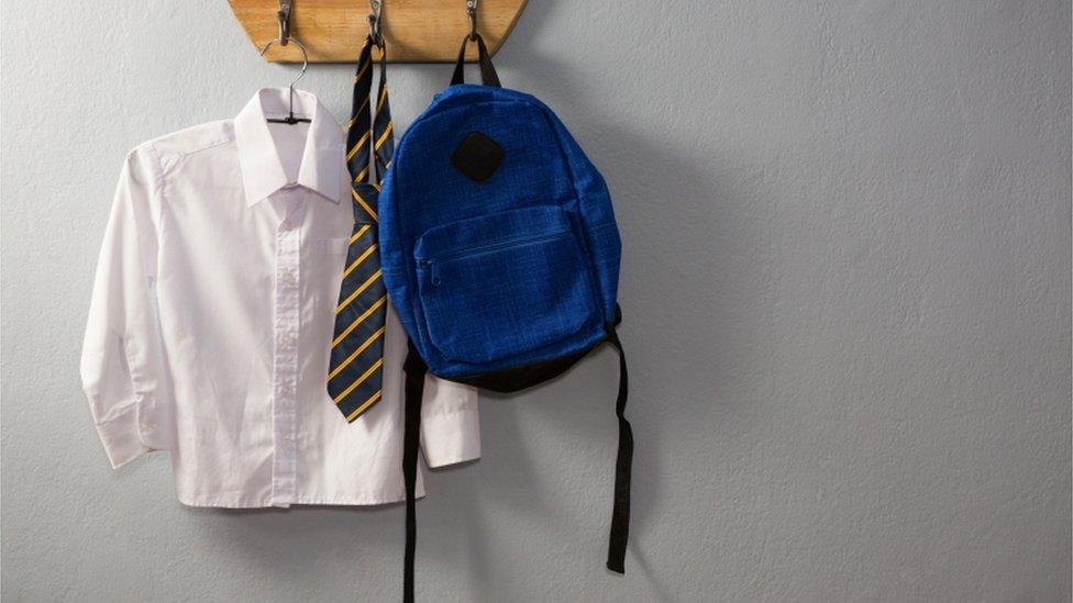 A shirt, tie and bag hanging on hooks