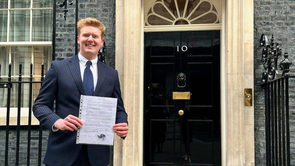 Mr Alexander holding the letter he carried on his previous running challenge outside 10 Downing Street