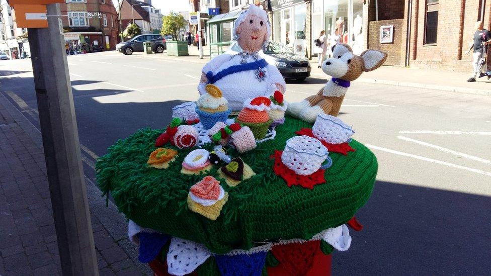 A knitted post box topper showing the Queen, a corgi and cakes in Crowborugh