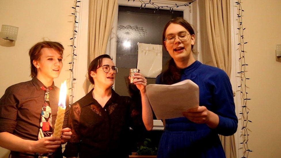 Three Jewish people performing havdalah in a living room