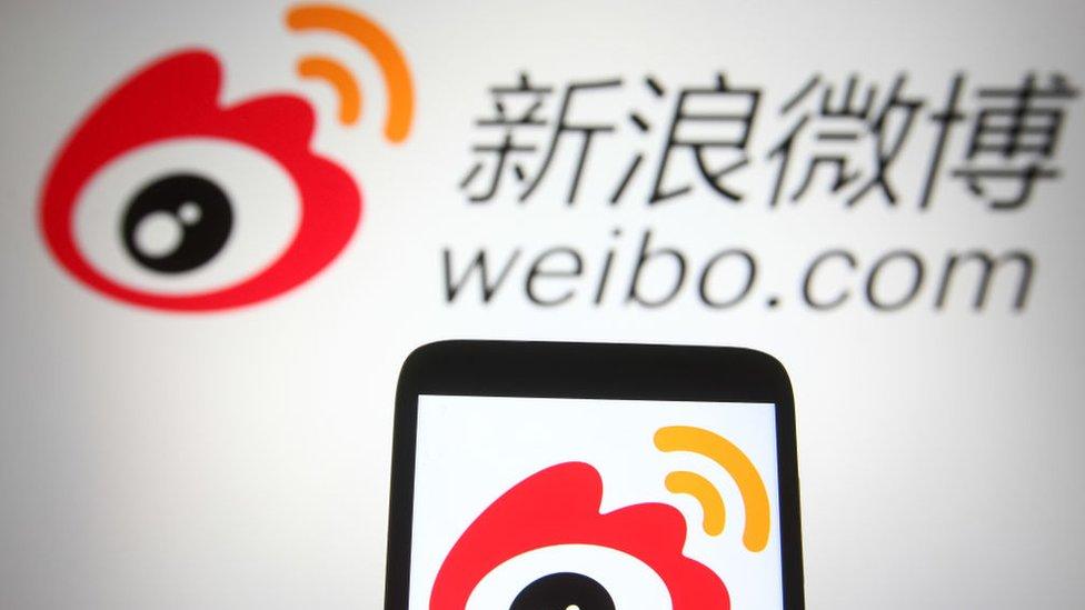 Weibo (Sina Weibo) logo of a Chinese social media platform is seen on a smartphone and a pc screen.