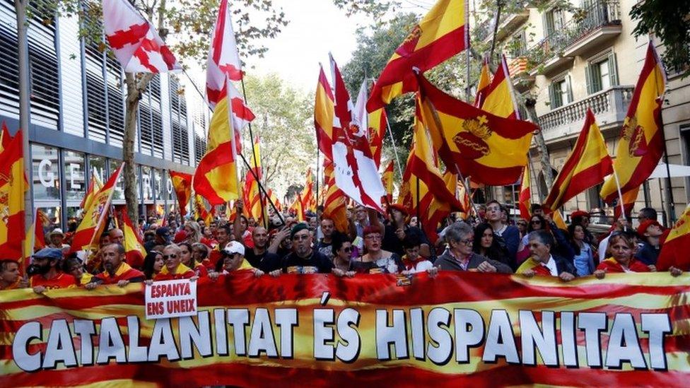 Demonstrators march with a 'Catalanitat es hispanitat' sign