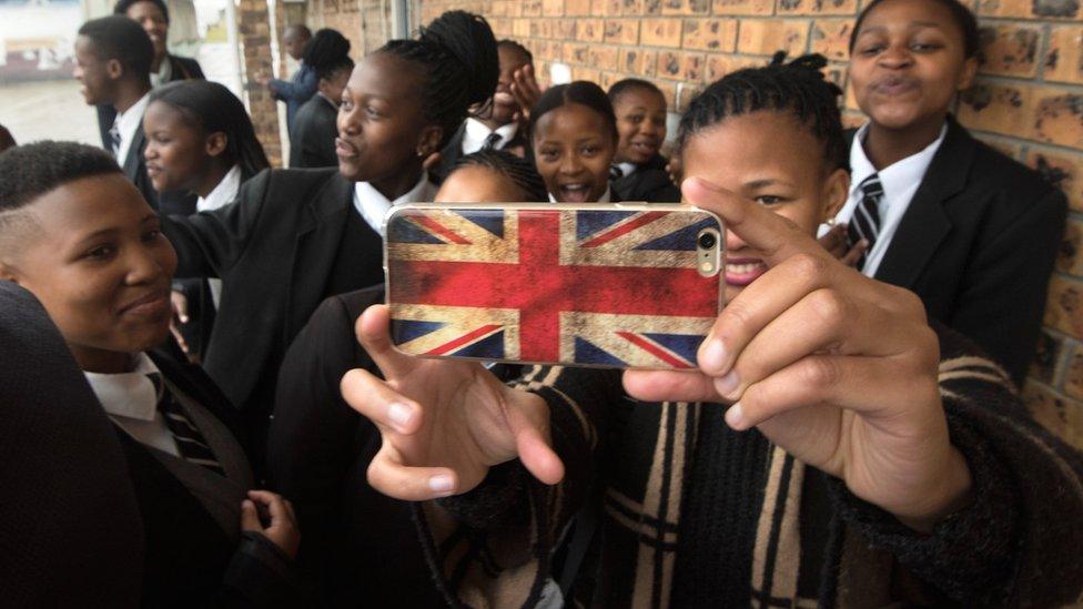 Schoolchildren, one with a phone decorated with the British flag, wait for UK Prime Minister Theresa May at the ID Mkhize Secondary School in Gugulethu, Cape Town, South Africa - Tuesday 28 August 2018