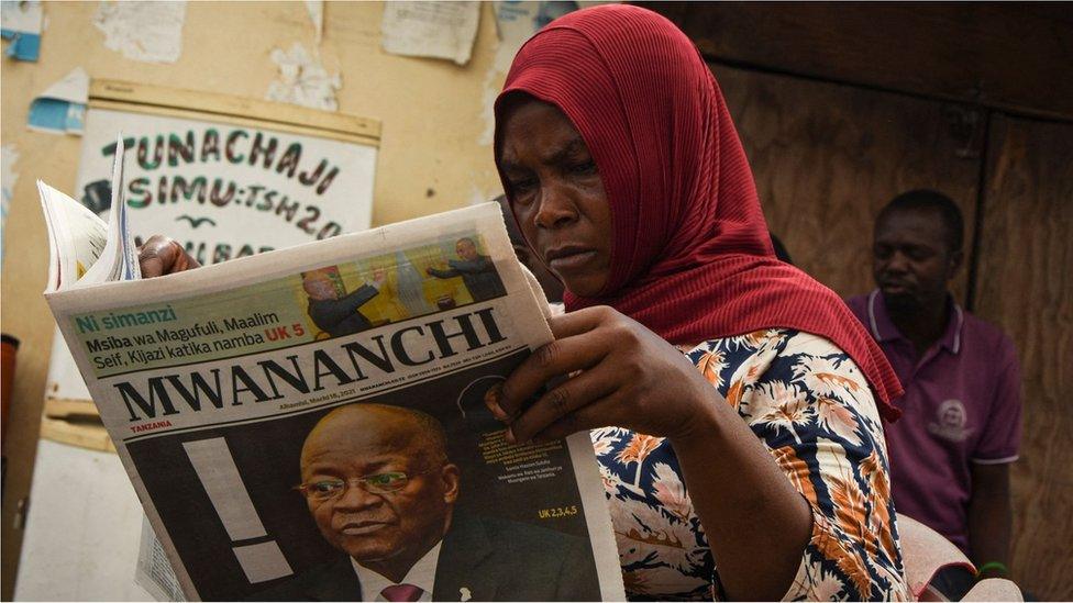 A woman reads a newspaper announcing the death of Tanzania's President John Magufuli in Dar es Salaam, on March 18, 2021.