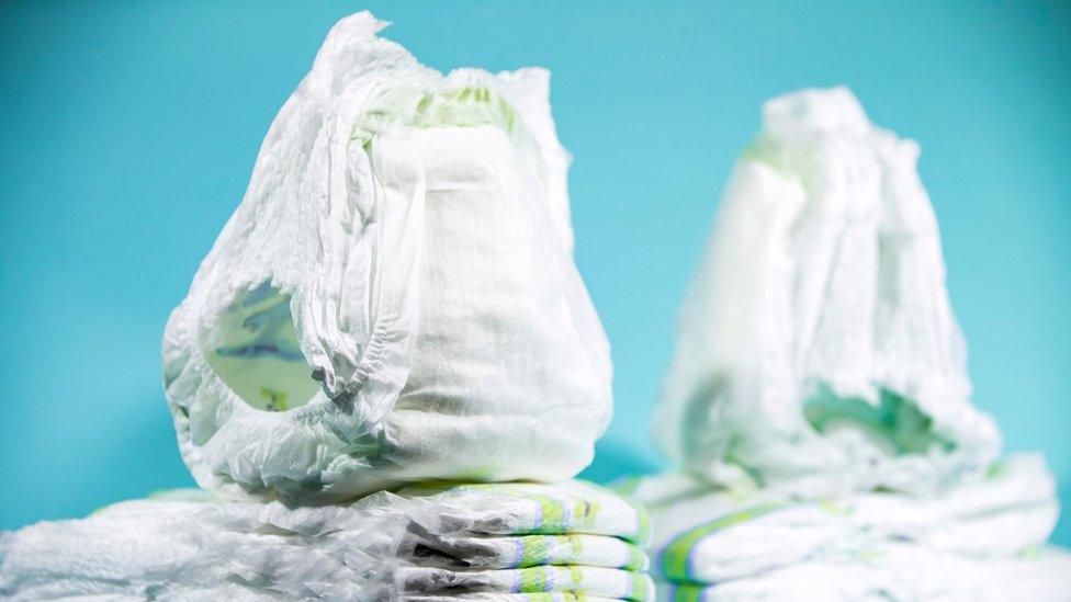 A stock photo shows unused disposable nappies in a stack against a blue background