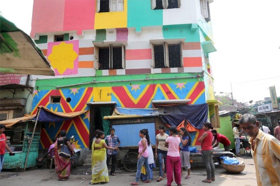 Indian commuters walk past a painted wall at Sonagachi red light district in Kolkata