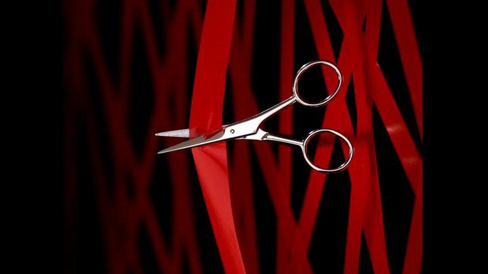 Scissors cutting red tape