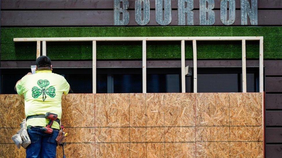 A worker boards the windows of a restaurant