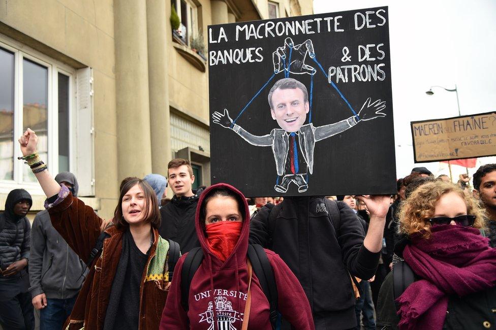 Protesters hold a placard reading "The macronette (a play of words with Macron and puppet in French) of bankers and bosses" on 27 April 27, in Rennes, France