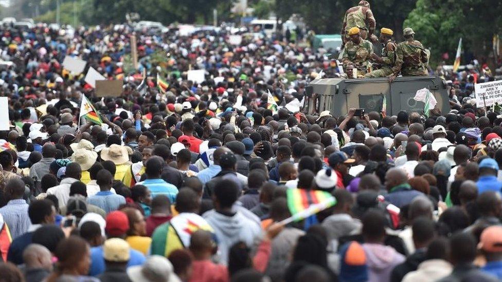 People march past an armoured personnel carrier in Harare (18 November 2017)