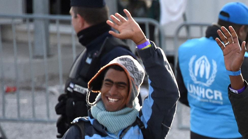 Migrants board a bus after leaving the camp