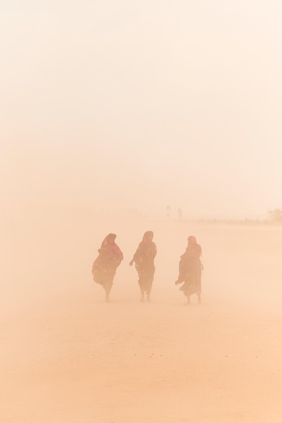 Three women walk through a sandstorm during the Cure Salee festival, in Ingall, northern Niger.