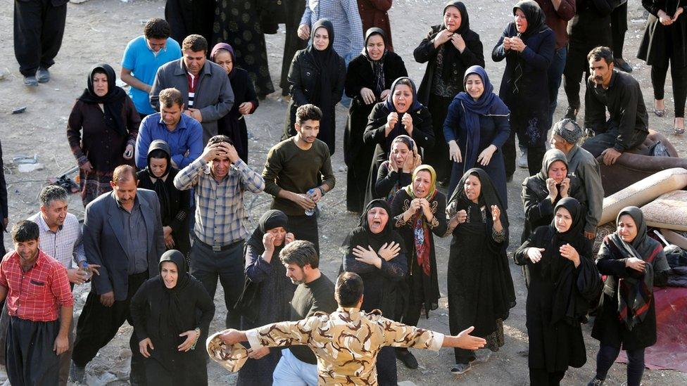 Iranian victims of the earthquake mourn and try to get closer to the body of a relative