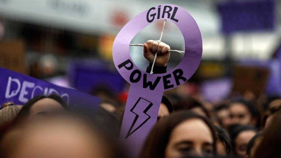 a protestor holds up a sign that reads 'girl power'