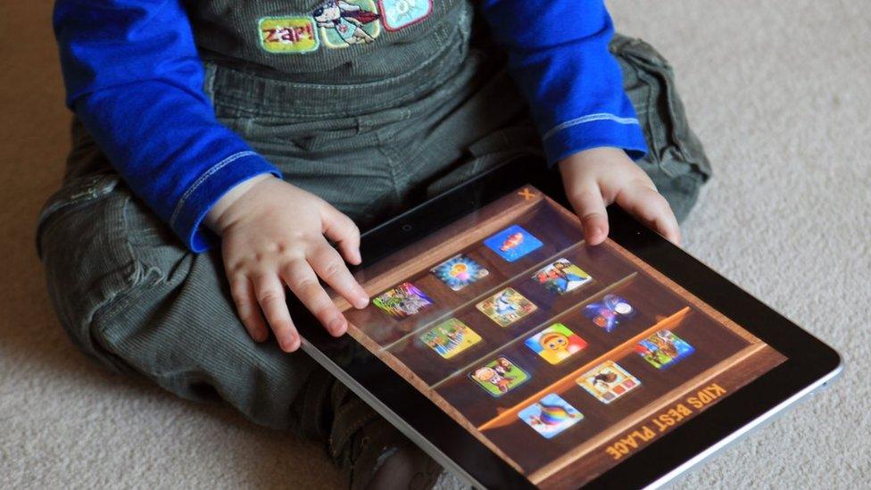 A toddler uses an iPad at his home