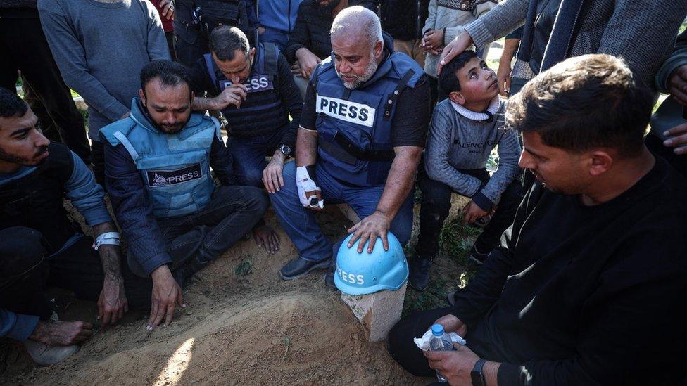 Al Jazeera Gaza bureau chief Wael al-Dahdouh places a blue "press" helmet on the grave of his son, Al Jazeera journalist Hamza al-Dahdouh, after he was killed in an Israeli air strike in Rafah, in the southern Gaza Strip (7 January 2024)