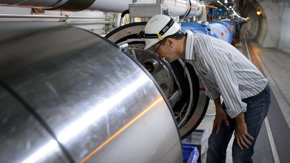 A scientist looks at a section of the European Organisation for Nuclear Research (CERN) Large Hadron Collider (LHC), during maintenance works on July 19, 2013 in Meyrin, near Geneva