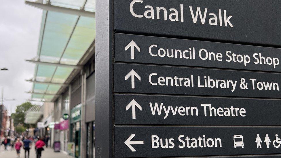 Swindon's Canal Walk sign post with shoppers in the background