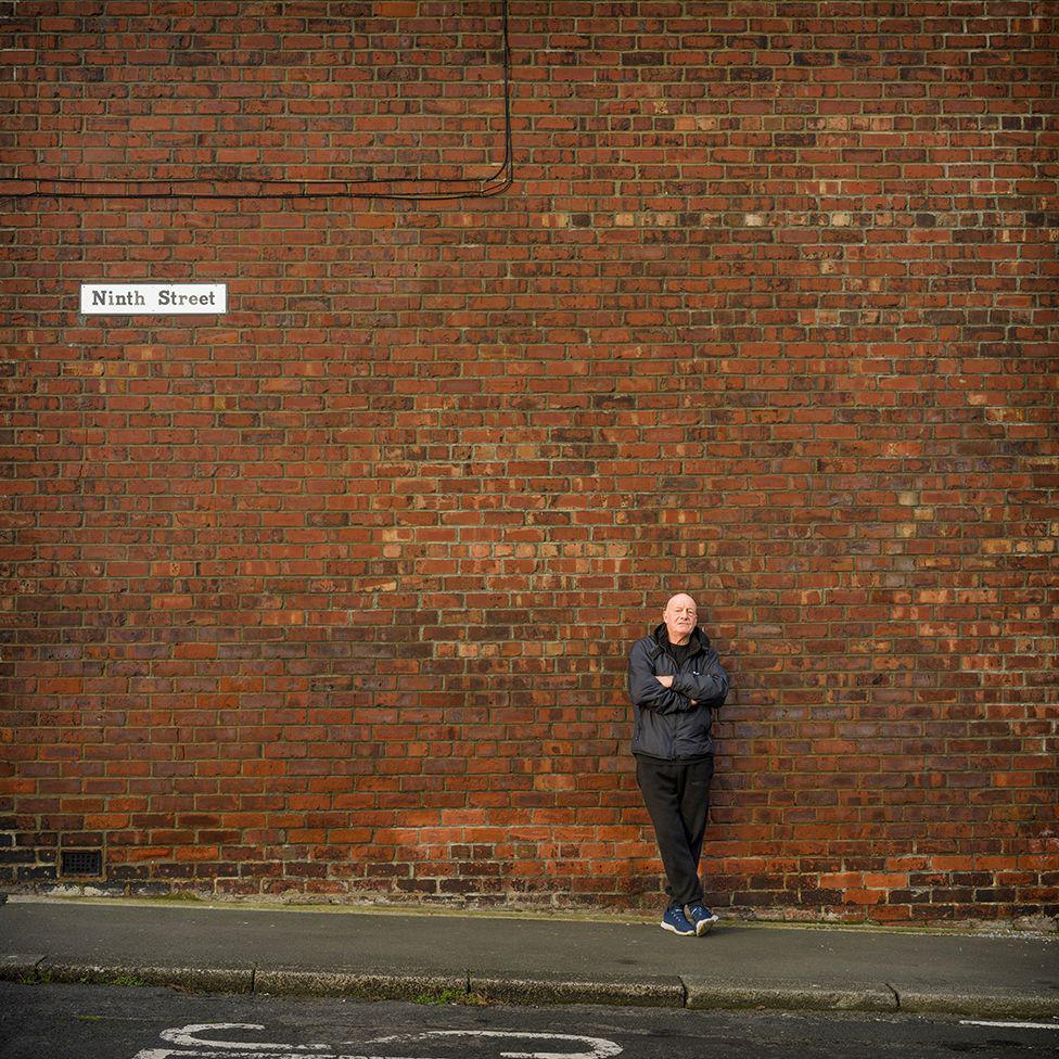 Former miner standing against a brick wall