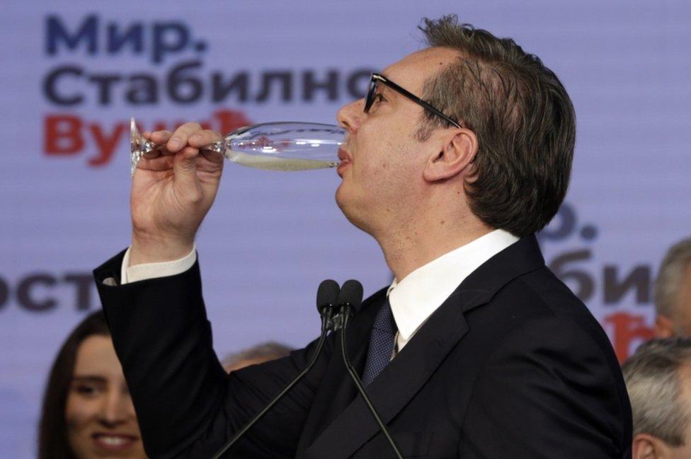 Serbian President Aleksandar Vucic drinks what appears to be champagne after the early results of the general elections in Belgrade, Serbia