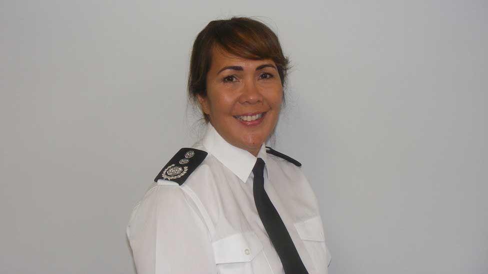 Louise Harrison, with brown hair in a ponytail wearing a white shirt with a black tie