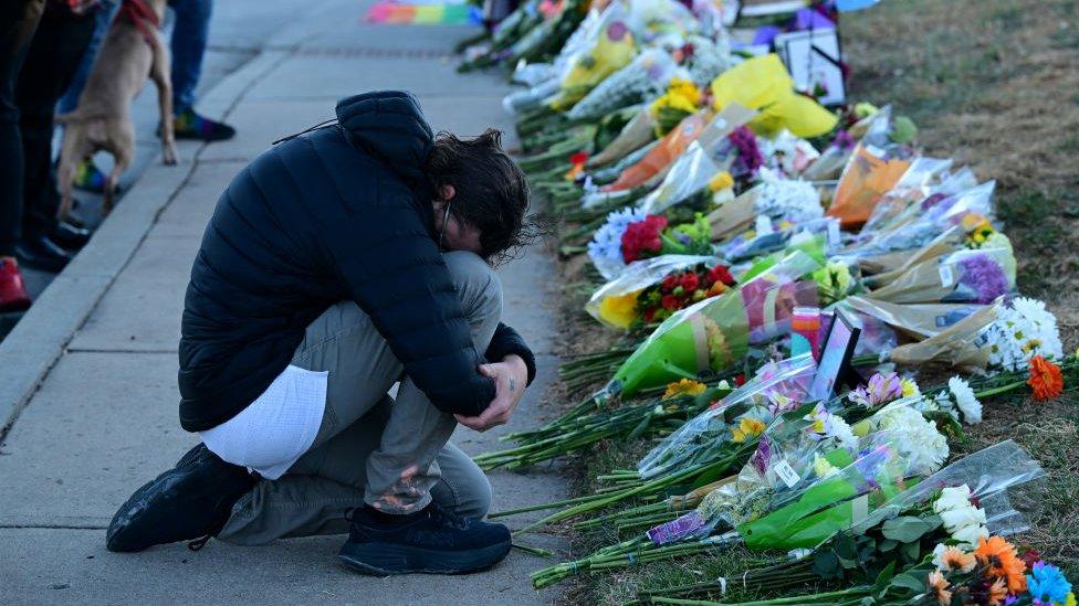 Winston Yellen places his head on his knees as he pays his respects at a makeshift memorial near Club Q on November 20, 2022 in Colorado Springs, Colorado.