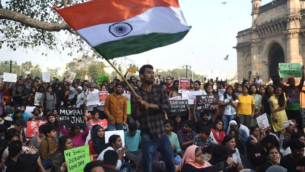 Protesters and students shout slogans and hold Indian flags as they protest against the violent clashes