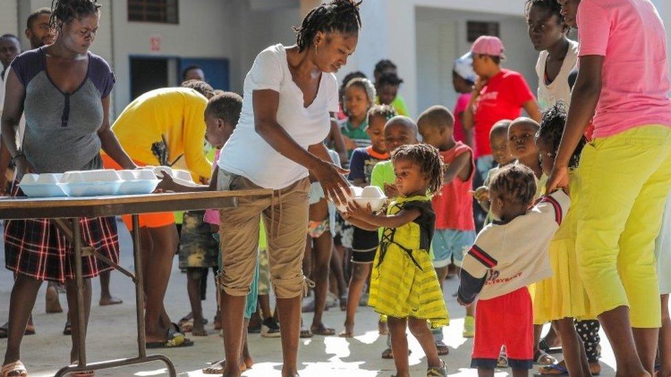 Haitian children who escaped violence in the town of Cite-Soleil line up to receive food, as they refuge at a school in Port-au-Prince