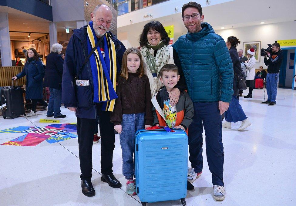 A family poses for a photograph after they are reunited at Belfast City Airport