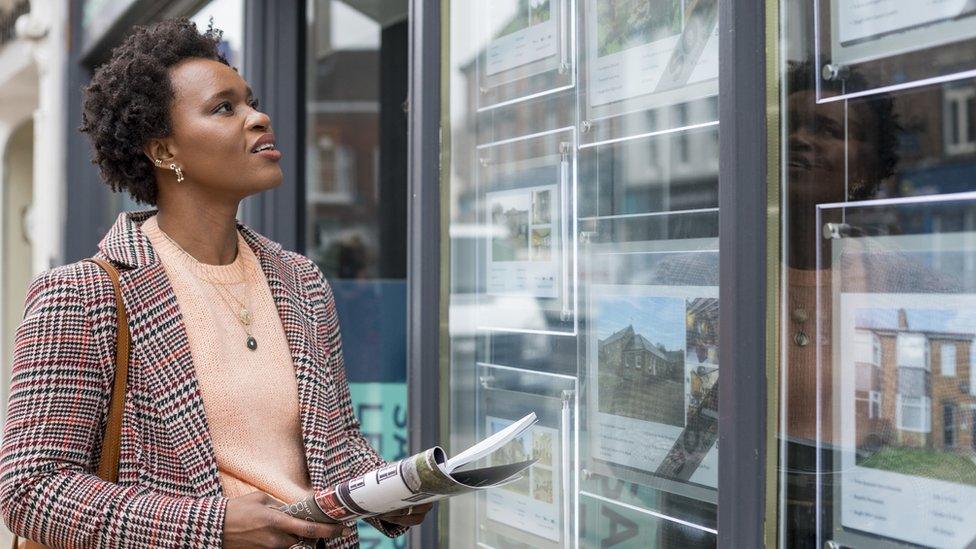 Woman looking in estate agent's window