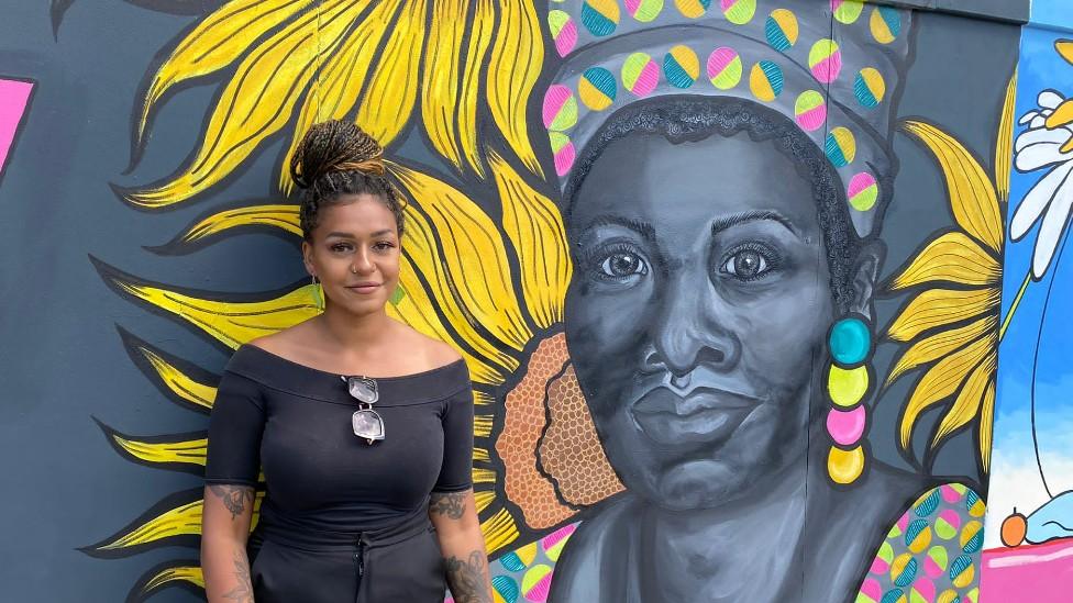 Lily Hammond in front of her mural at Ipswich waterfront of Maya Angelou