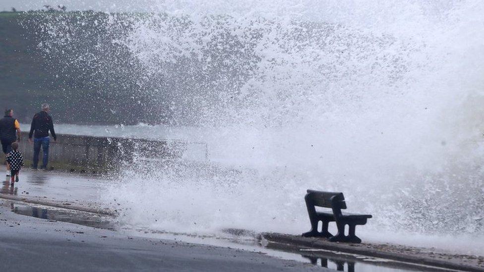 Waves crash over wall