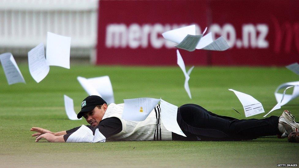 New Zealand cricketer with lots of papers blowing around him