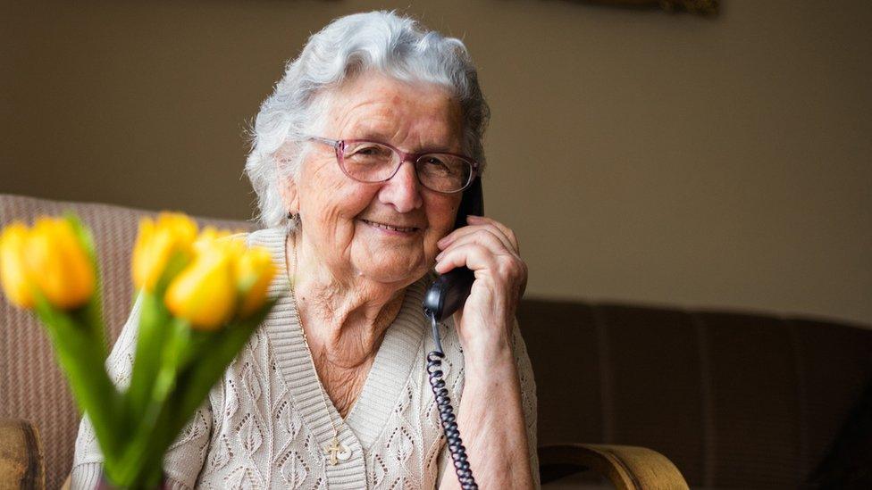 Stock image of an elderly woman using a landline phone