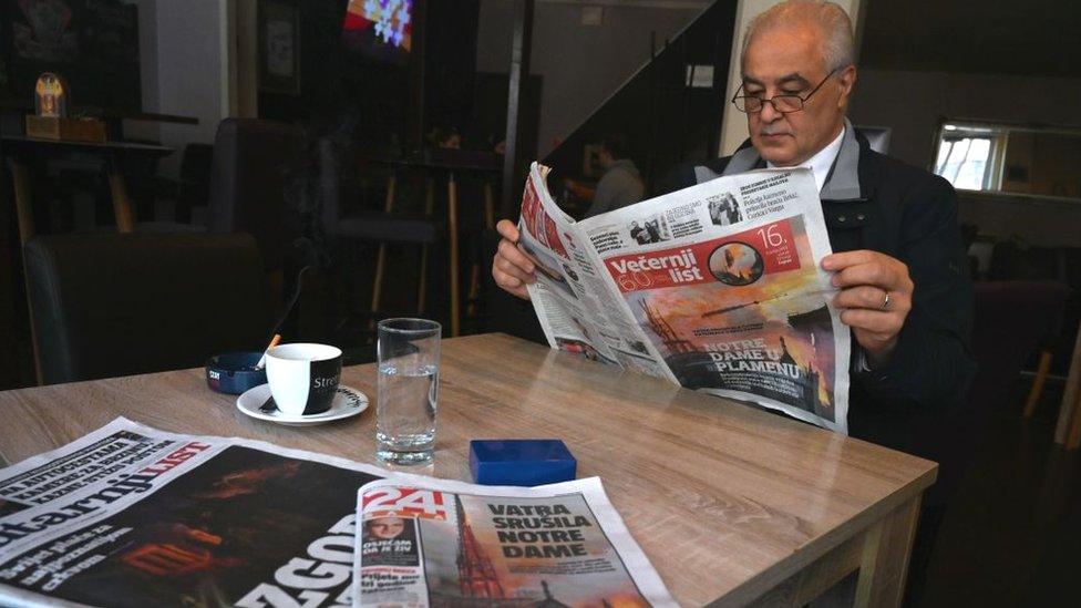 A Croatian man reads a daily newspapers with front page coverage of the Notre-Dame Cathedral fire in Paris, in Zagreb, on April 16, 2019