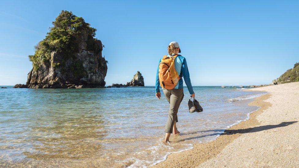 A women walks on a beach in the Abel Tasman National Park in New Zealand