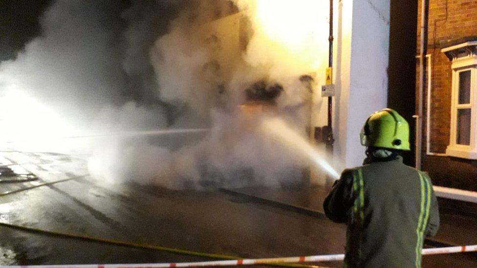 Firefighter spraying a burning building