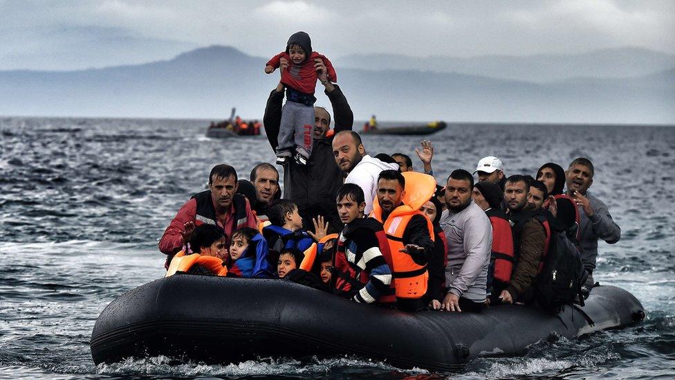 A man holds up a young boy as a boat carrying migrants and refugees arrives at the Greek island of Lesbos after crossing the Aegean sea from Turkey on October 21, 2015